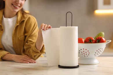 Photo of Woman using paper towels at white marble table in kitchen, closeup