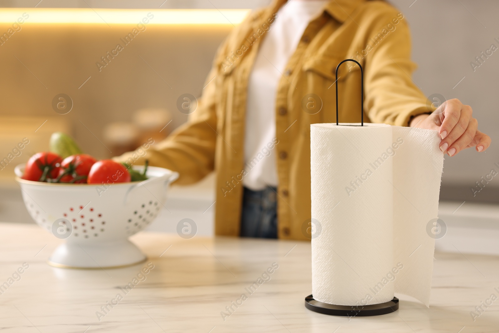 Photo of Woman using paper towels at white marble table in kitchen, closeup