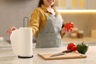 Photo of Woman with bell pepper using paper towels at white marble table in kitchen, closeup