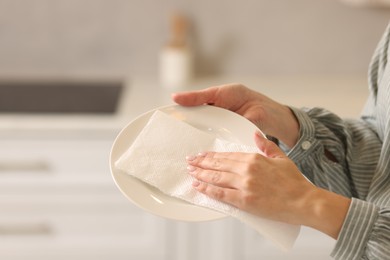 Photo of Woman wiping plate with paper towel in kitchen, closeup