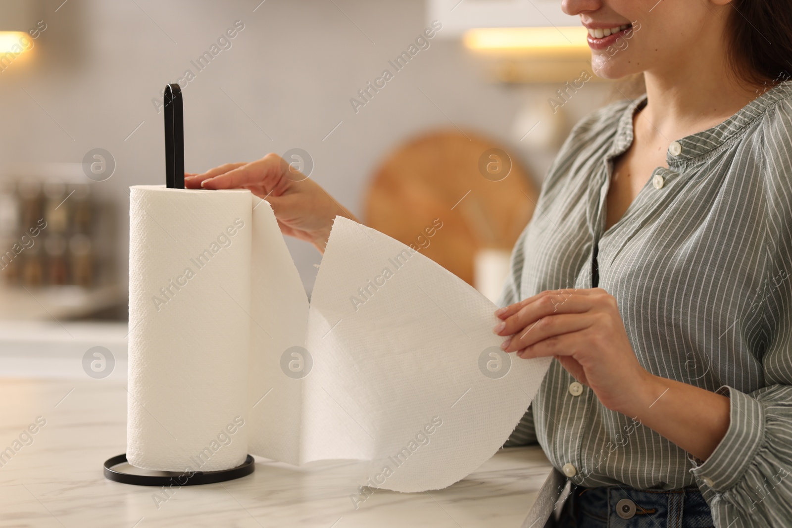 Photo of Woman using paper towels at white marble table in kitchen, closeup