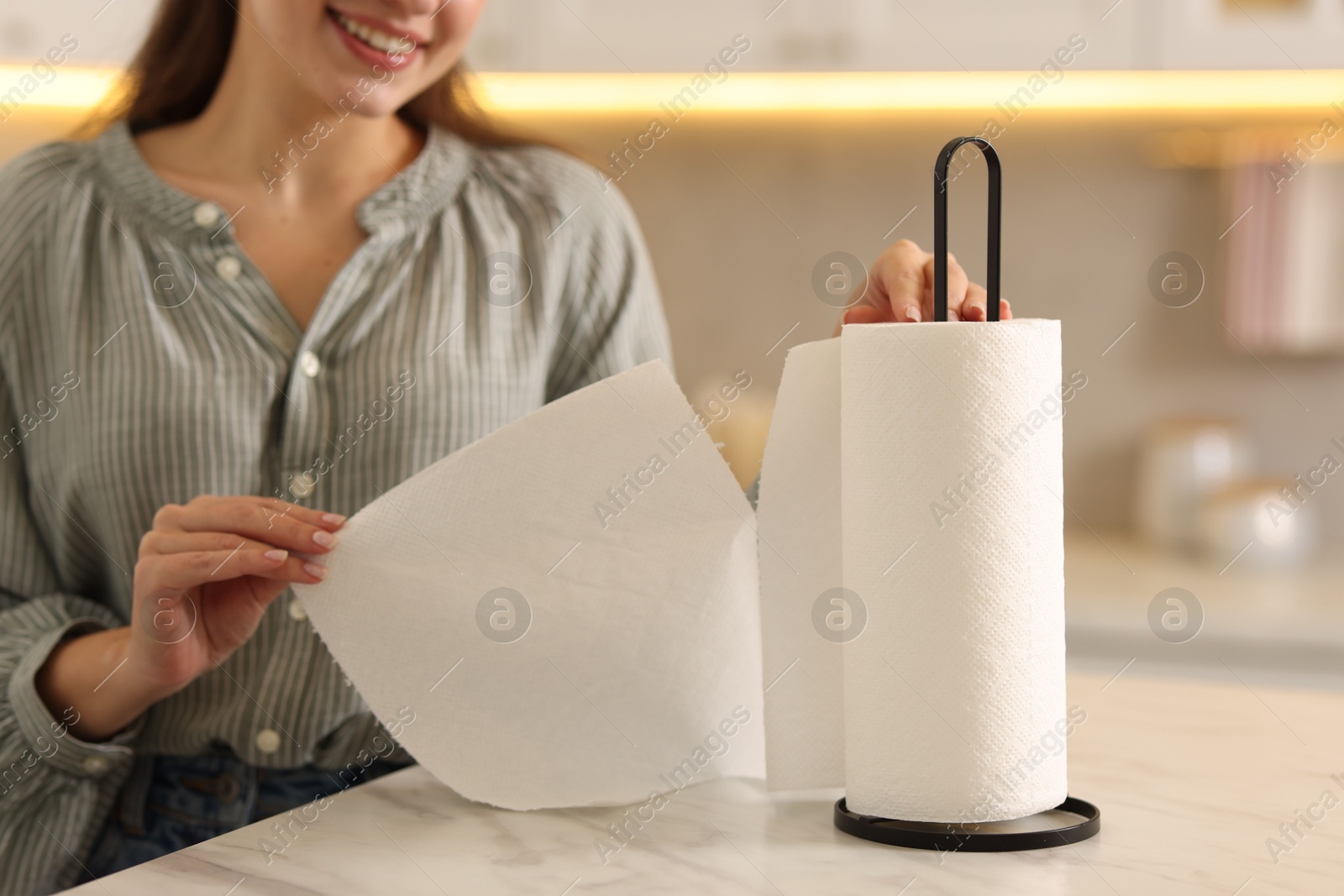 Photo of Woman using paper towels at white marble table in kitchen, closeup