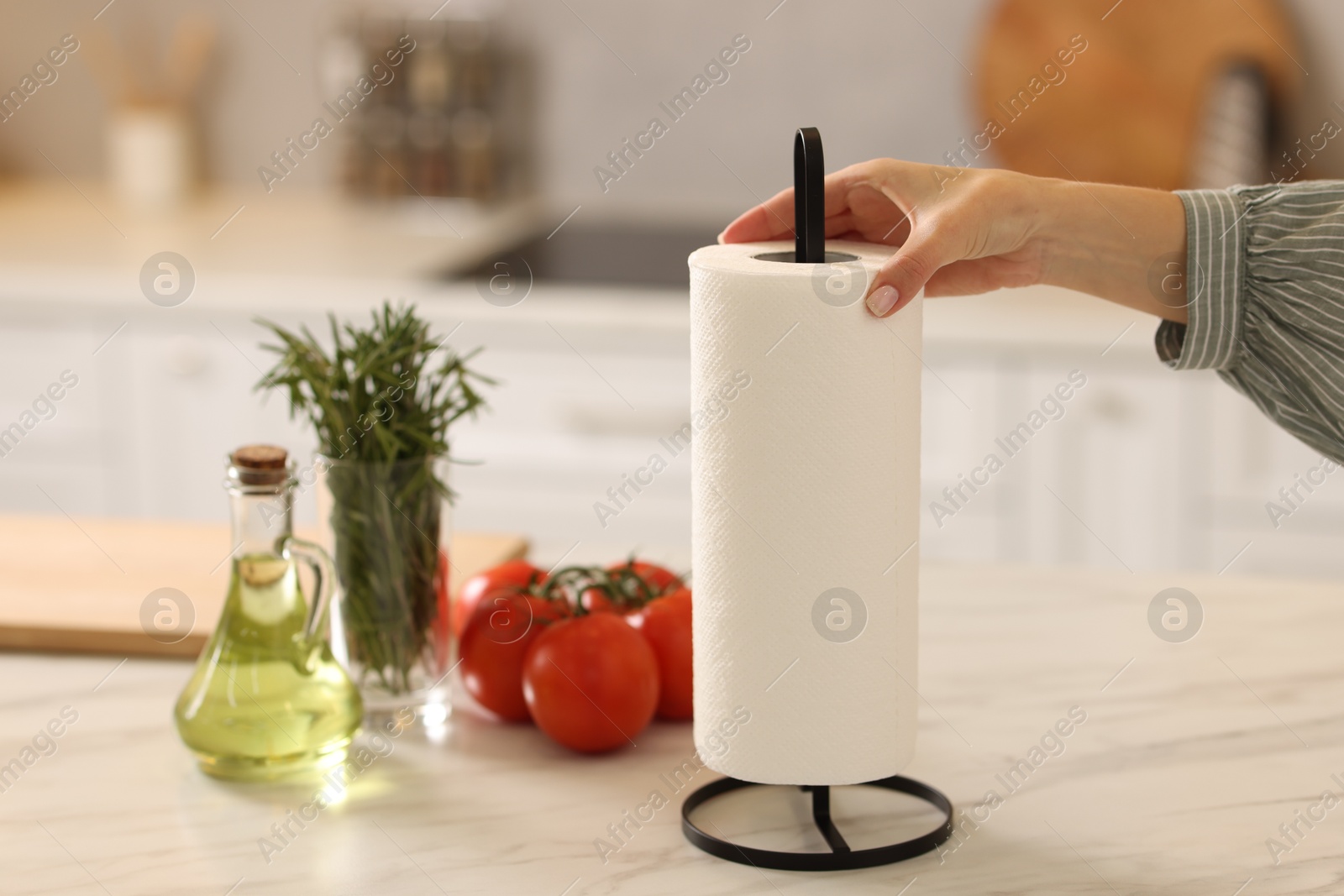 Photo of Woman using paper towels at white marble table in kitchen, closeup