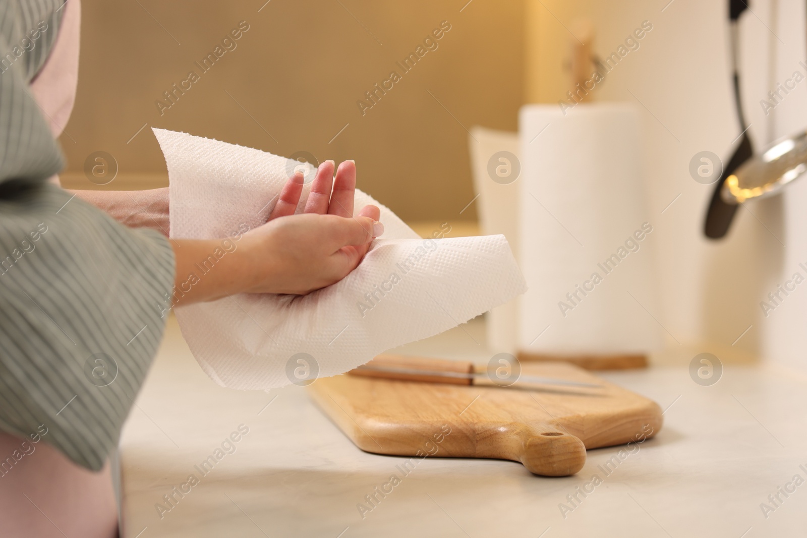 Photo of Woman wiping hands with paper towel in kitchen, closeup