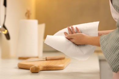 Photo of Woman wiping hands with paper towel in kitchen, closeup