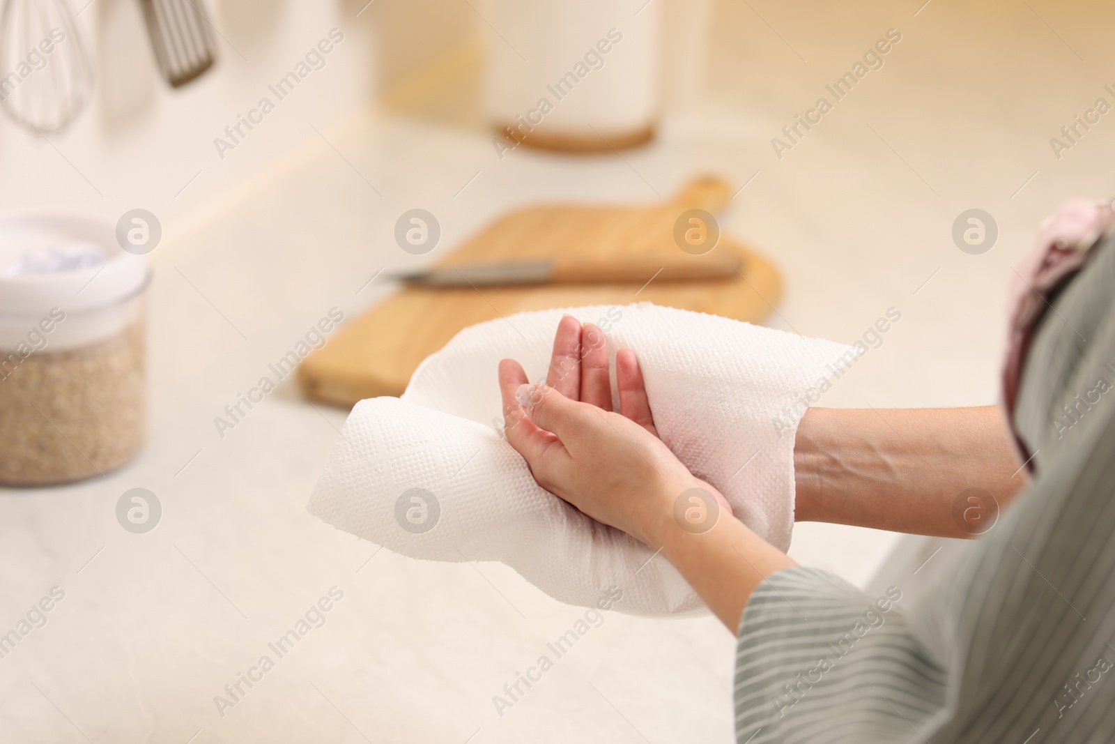 Photo of Woman wiping hands with paper towel in kitchen, closeup