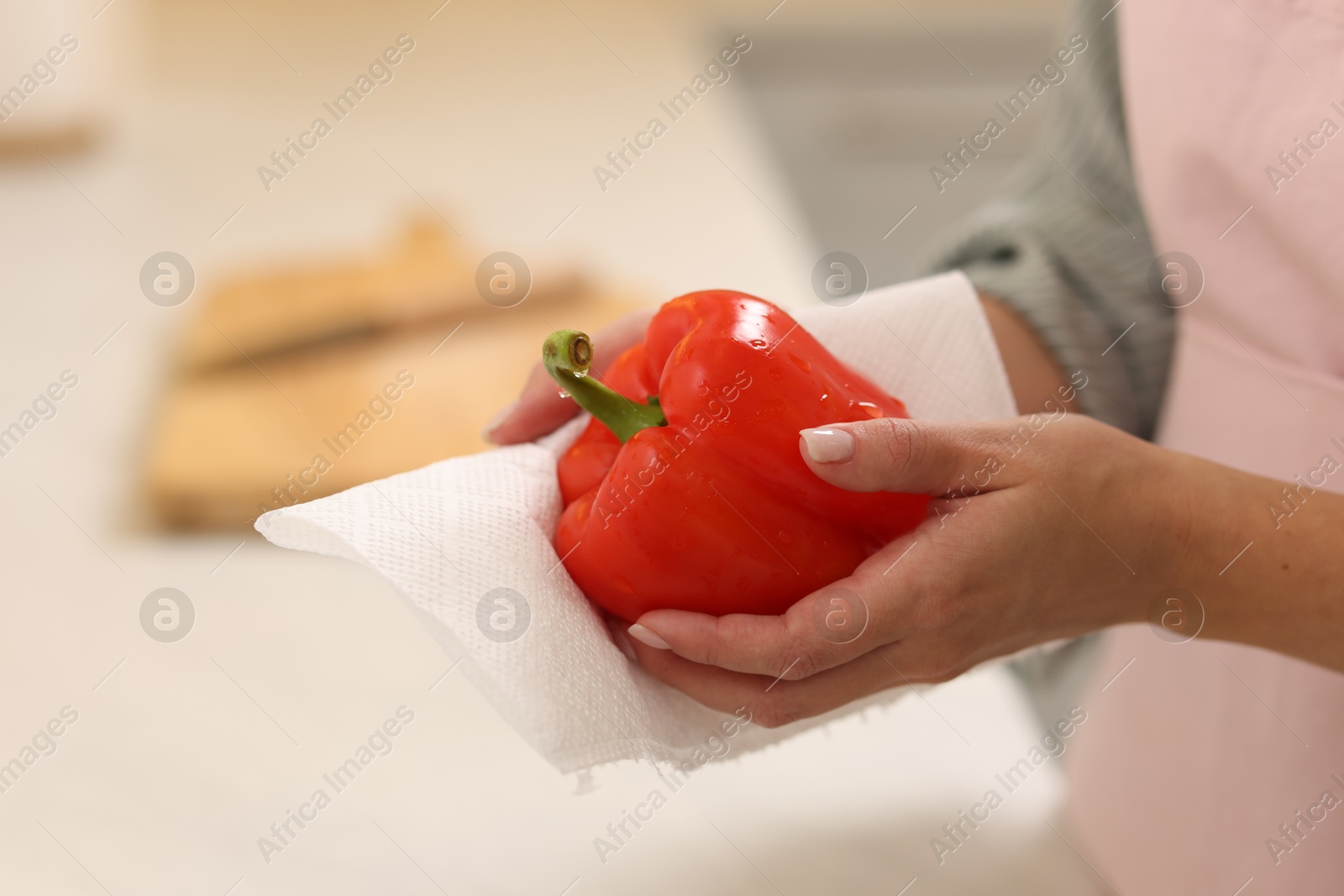 Photo of Woman wiping bell pepper with paper towel in kitchen, closeup