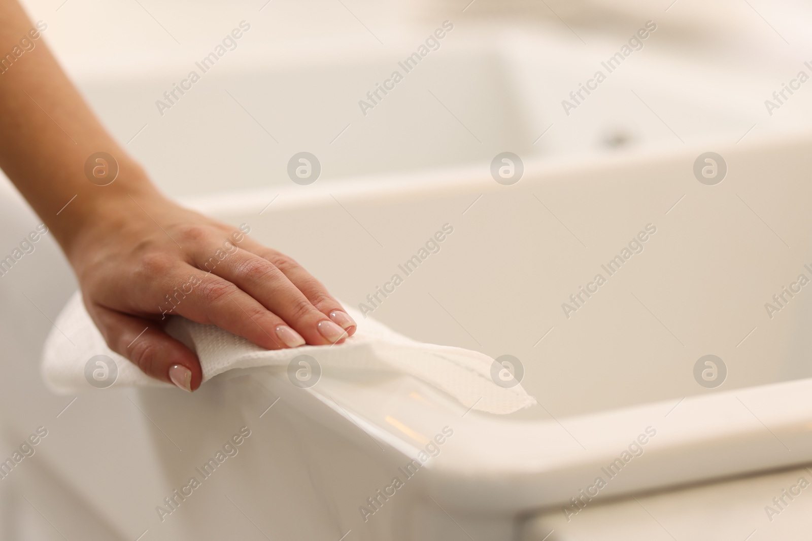 Photo of Woman cleaning sink with paper towel in kitchen, closeup