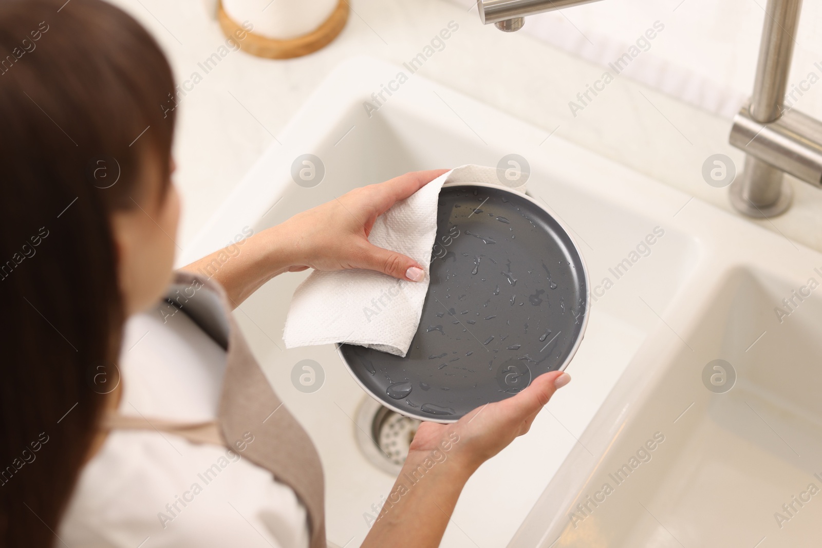 Photo of Woman wiping plate with paper towel in kitchen, above view