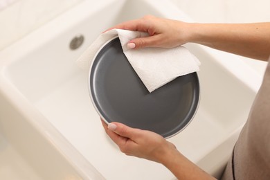 Photo of Woman wiping plate with paper towel in kitchen, above view