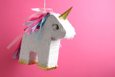 Photo of Bright pinata in shape of unicorn hanging on pink background