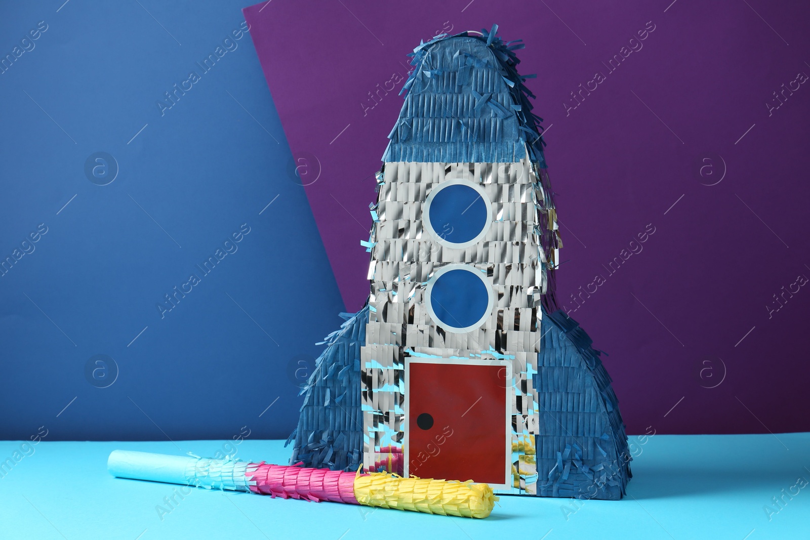 Photo of Bright pinata in shape of spaceship and stick on color background