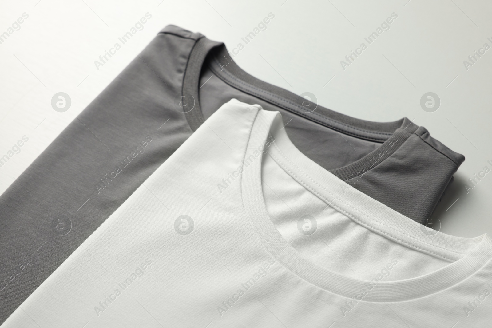 Photo of Different blank t-shirts on white background, closeup. Mockup for design