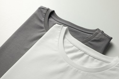 Photo of Different blank t-shirts on white background, closeup. Mockup for design