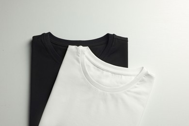 Different blank t-shirts on white background, top view. Mockup for design