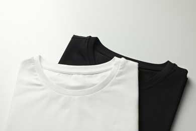 Photo of Different blank t-shirts on white background above view. Mockup for design