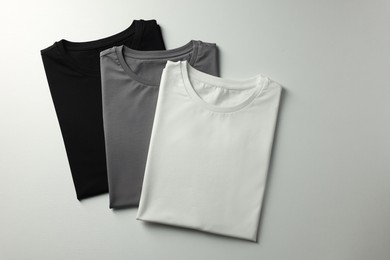 Different blank t-shirts on white background, top view. Mockup for design