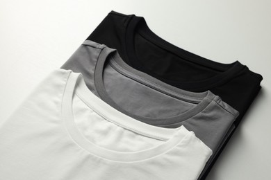 Photo of Different blank t-shirts on white background, closeup. Mockup for design