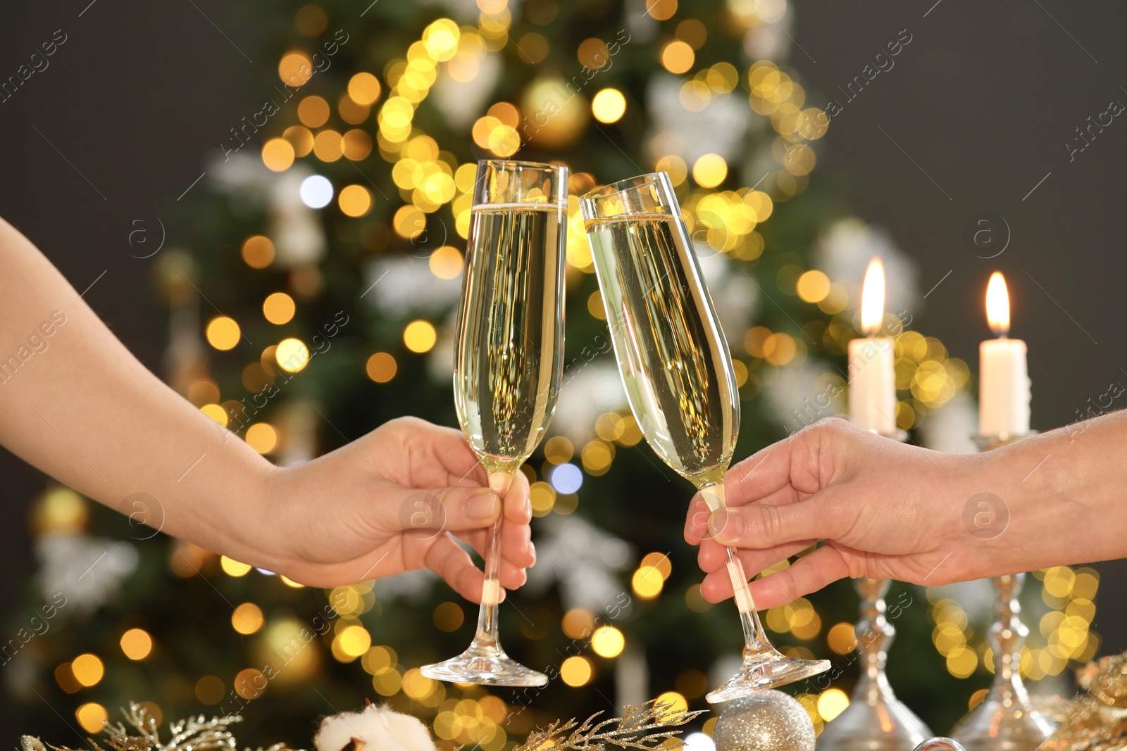 Photo of Women with glasses of champagne against blurred Christmas lights, closeup. Bokeh effect