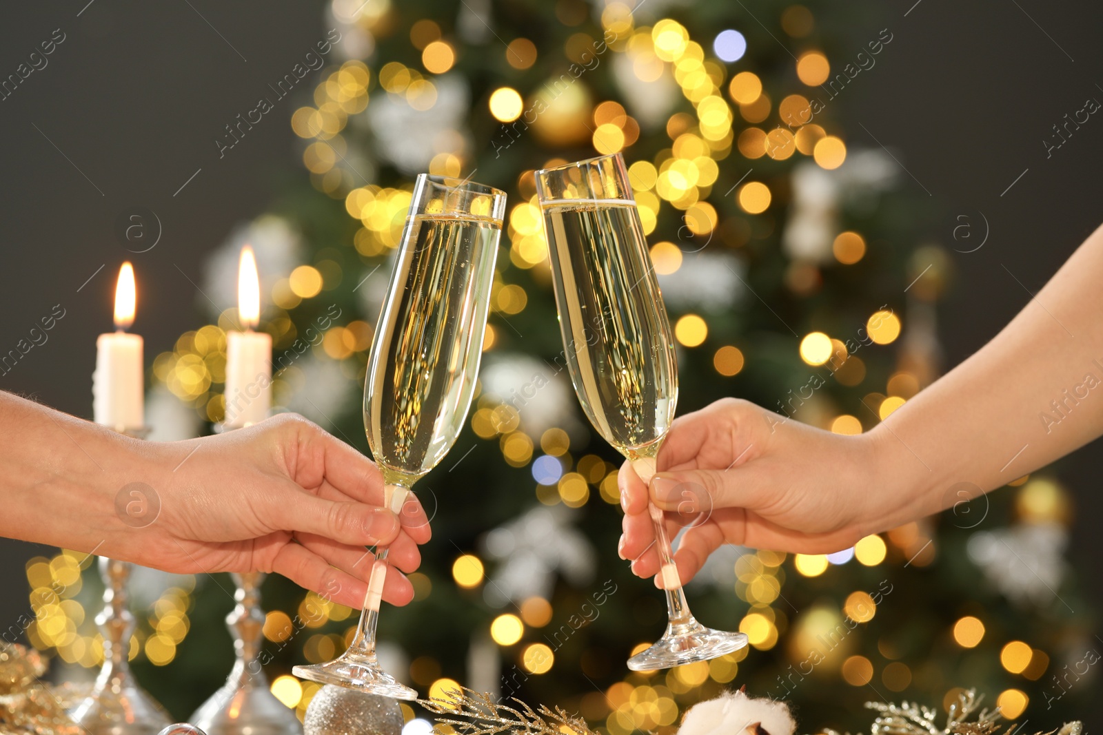 Photo of Women with glasses of champagne against blurred Christmas lights, closeup. Bokeh effect