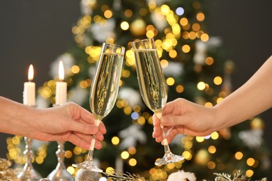 Photo of Women with glasses of champagne against blurred Christmas lights, closeup. Bokeh effect