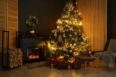 Photo of Christmas tree with festive decor, presents and fireplace in cozy room