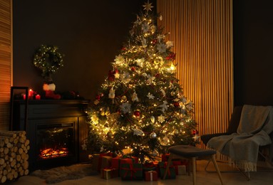 Photo of Christmas tree with festive decor, presents, fireplace and armchair in cozy room