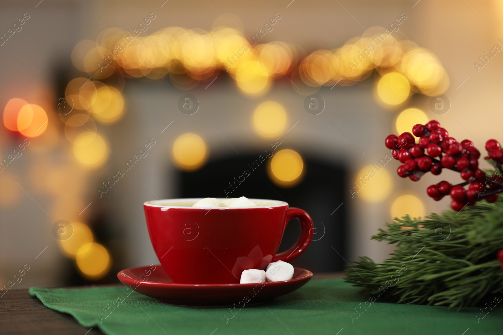 Photo of Tasty cocoa with marshmallows in cup and decor on table against blurred Christmas lights, bokeh effect