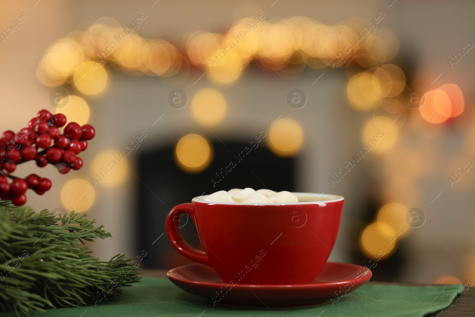 Photo of Tasty cocoa with marshmallows in cup and decor on table against blurred Christmas lights, bokeh effect