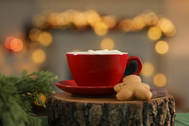 Photo of Tasty cocoa with marshmallows in cup, cookies and decor on table against blurred Christmas lights, closeup. Bokeh effect