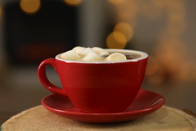 Photo of Tasty cocoa with marshmallows in cup on stump, closeup. Christmas drink