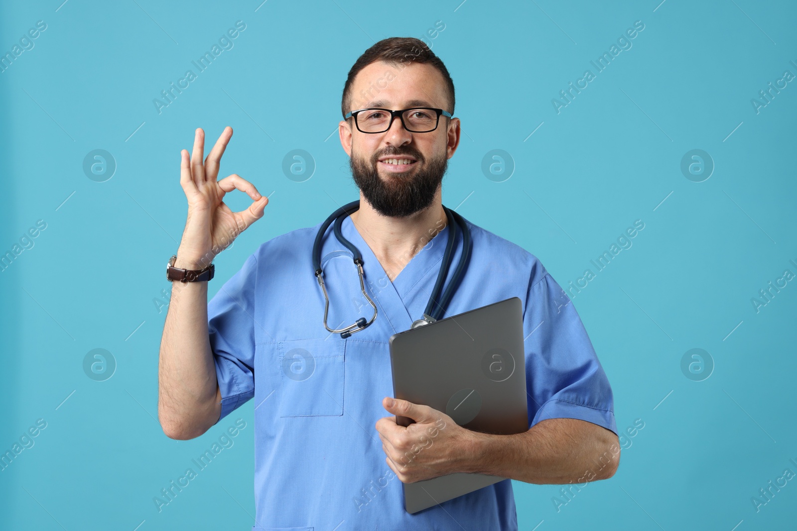 Photo of Doctor with laptop showing okay gesture on light blue background