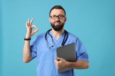 Photo of Doctor with laptop showing okay gesture on light blue background