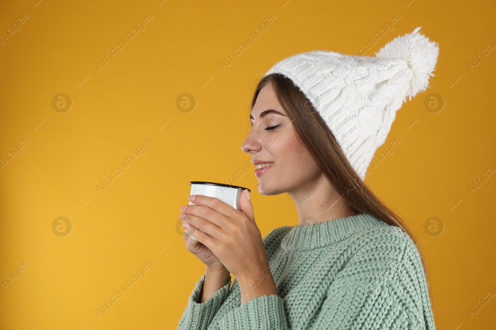 Photo of Happy beautiful woman with mug of mulled wine on yellow background