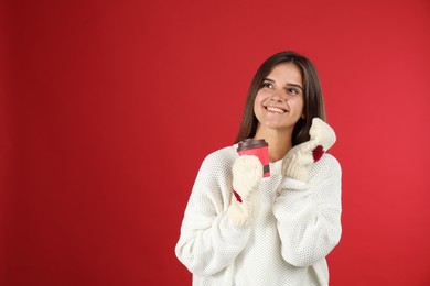 Photo of Happy beautiful woman with paper cup of mulled wine on red background. Space for text