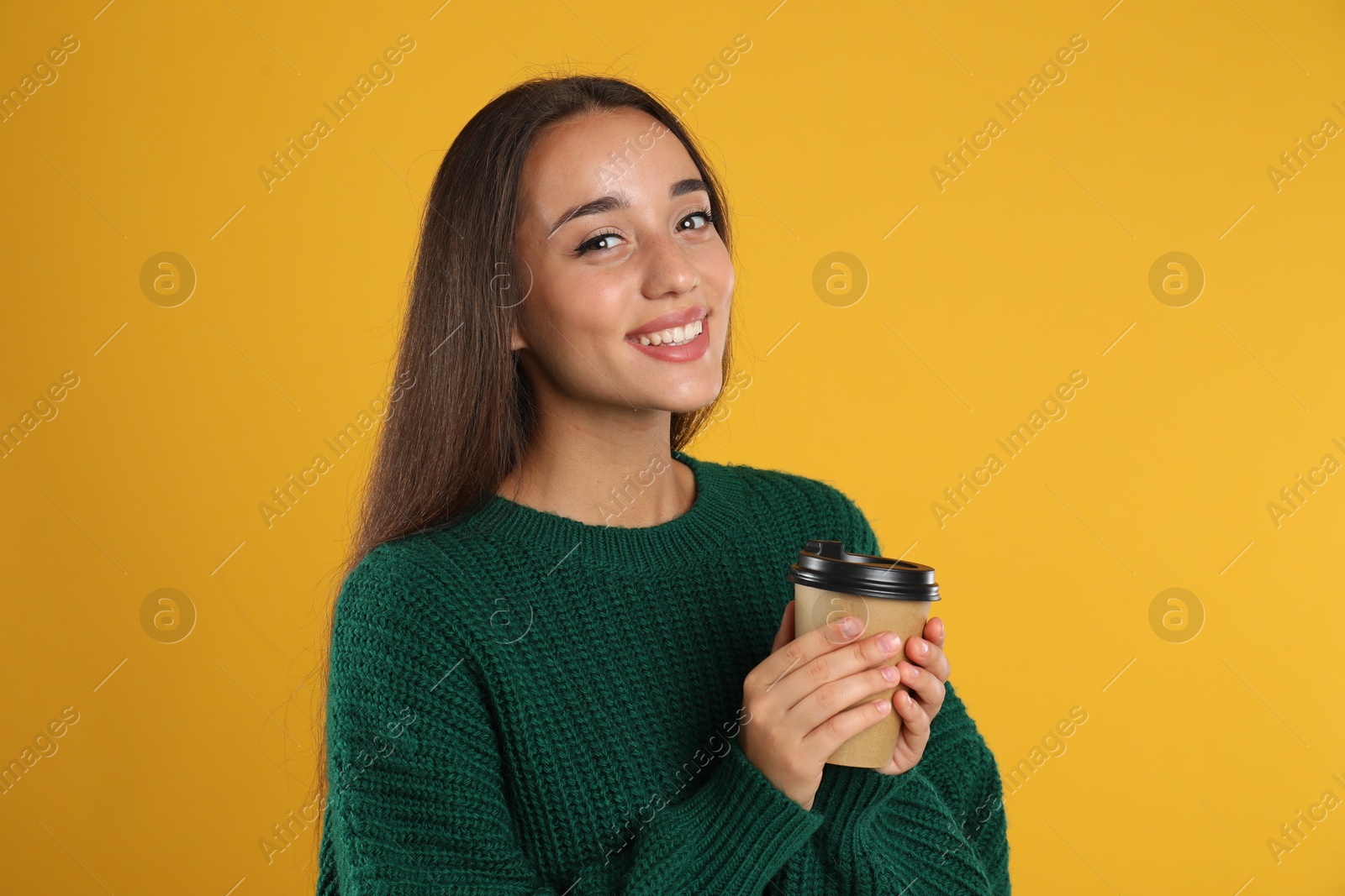 Photo of Happy beautiful woman with paper cup of mulled wine on yellow background