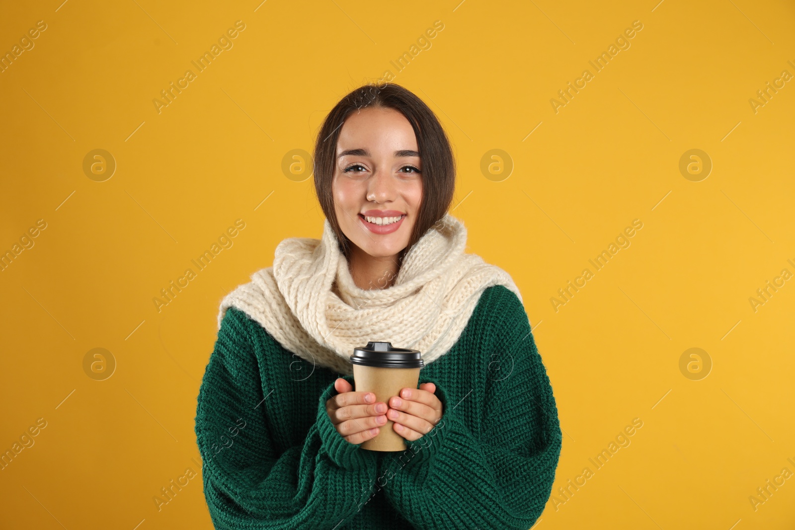 Photo of Happy beautiful woman with paper cup of mulled wine on yellow background