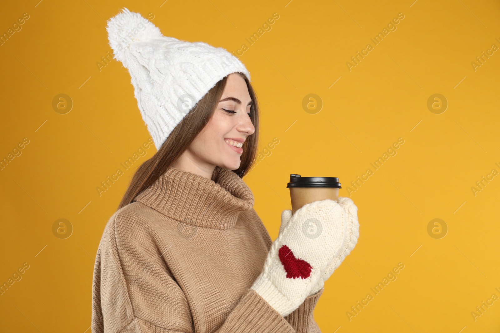 Photo of Happy beautiful woman with paper cup of mulled wine on yellow background