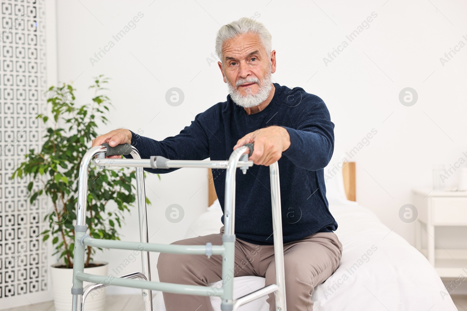 Photo of Senior man with walking frame on bed in hospital ward