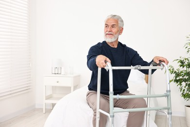 Photo of Senior man with walking frame on bed in hospital ward. Space for text