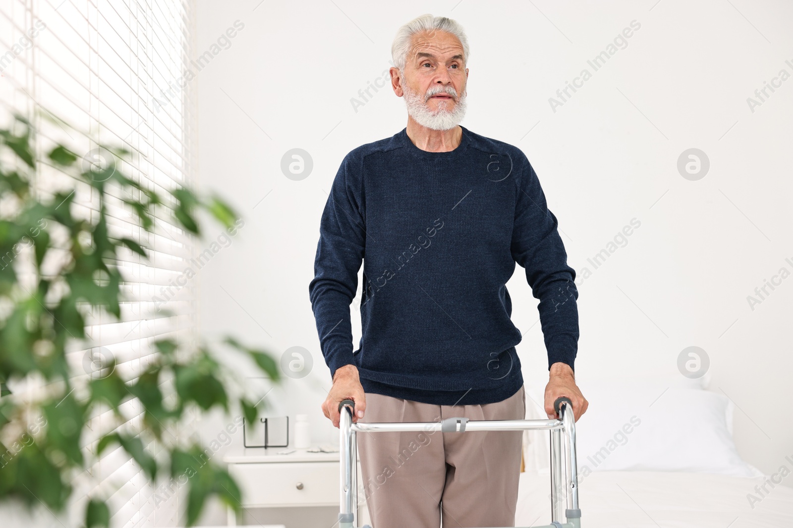 Photo of Senior man with walking frame in hospital ward