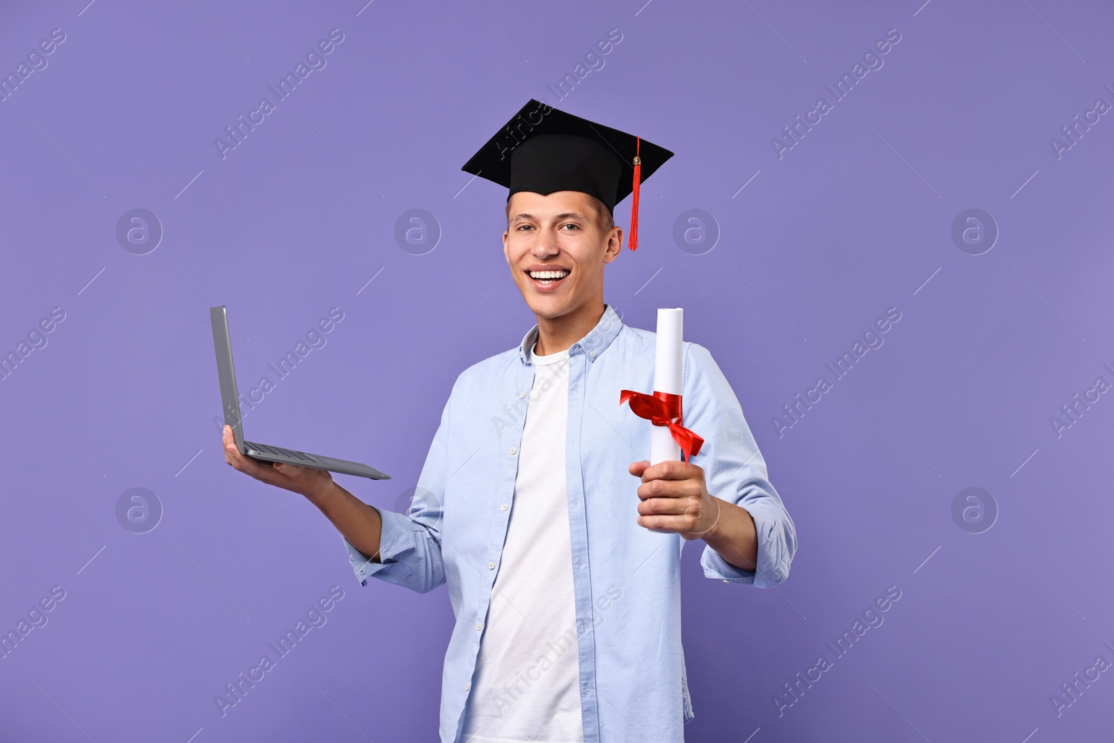 Photo of Happy student with laptop and diploma after graduation on violet background