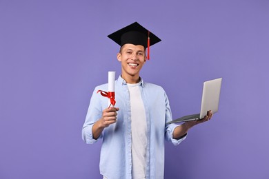 Photo of Happy student with laptop and diploma after graduation on violet background