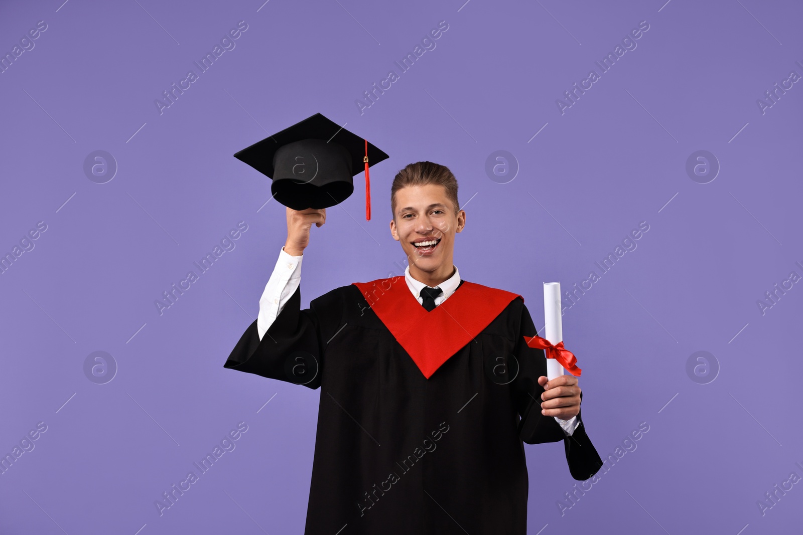 Photo of Happy student with hat and diploma after graduation on violet background