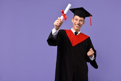 Photo of Happy student with diploma after graduation on violet background. Space for text