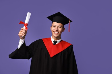 Photo of Happy student with diploma after graduation on violet background