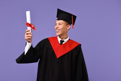 Photo of Happy student with diploma after graduation on violet background