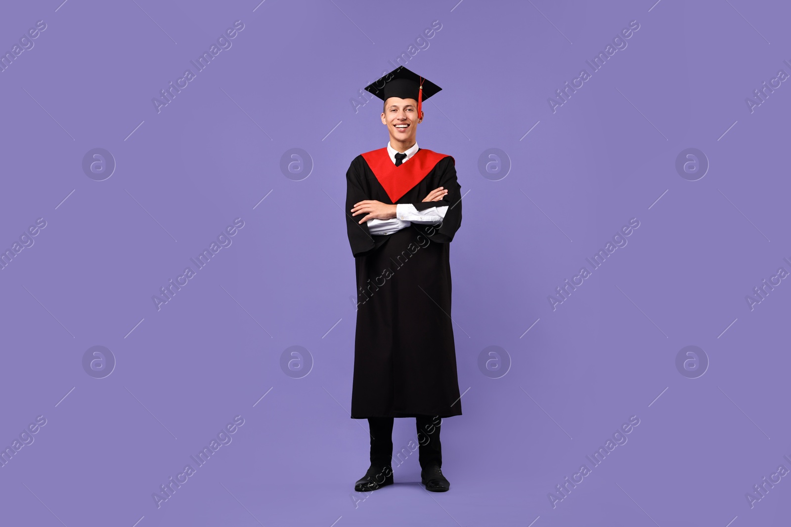 Photo of Happy student with crossed arms after graduation on violet background