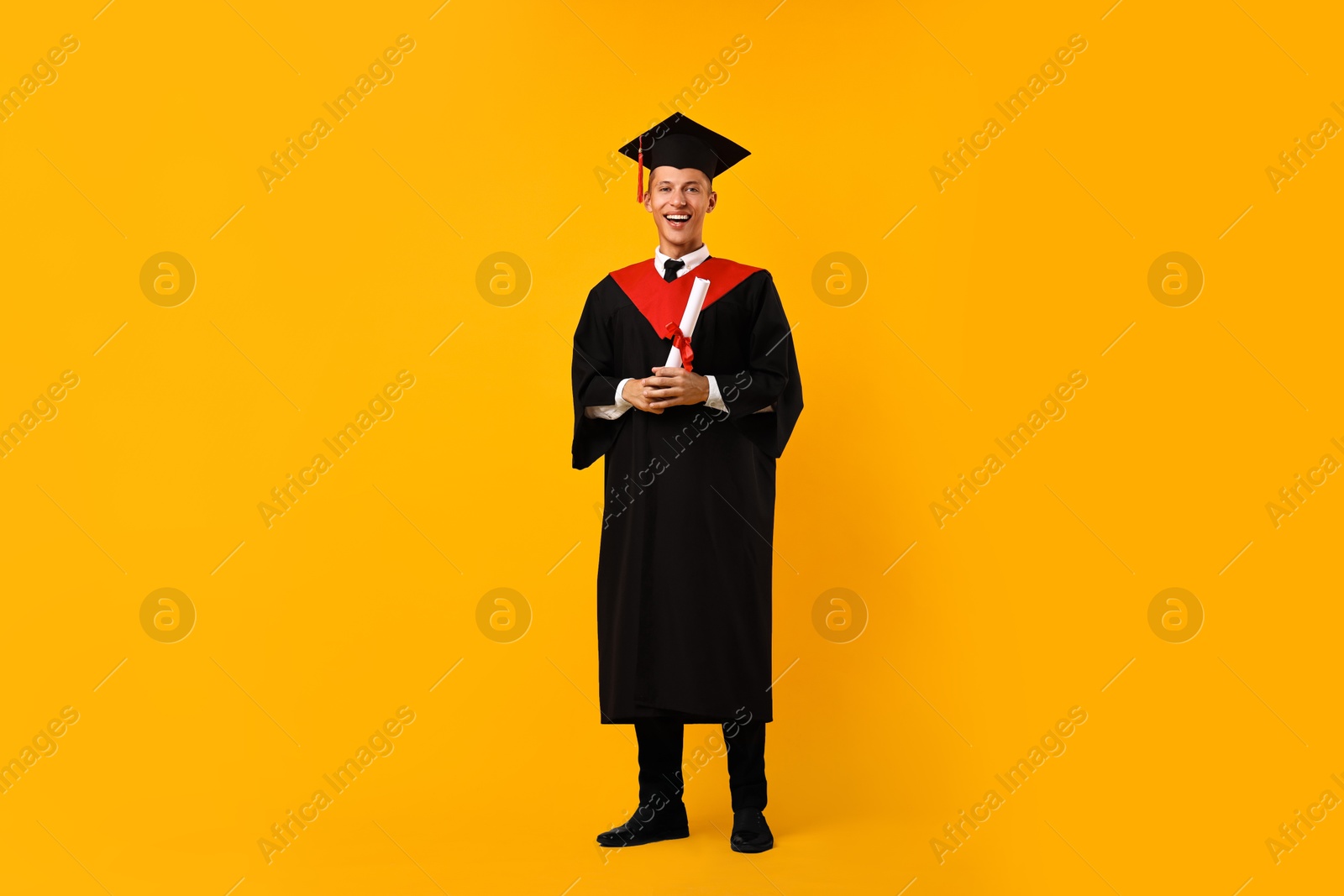 Photo of Happy student with diploma after graduation on orange background