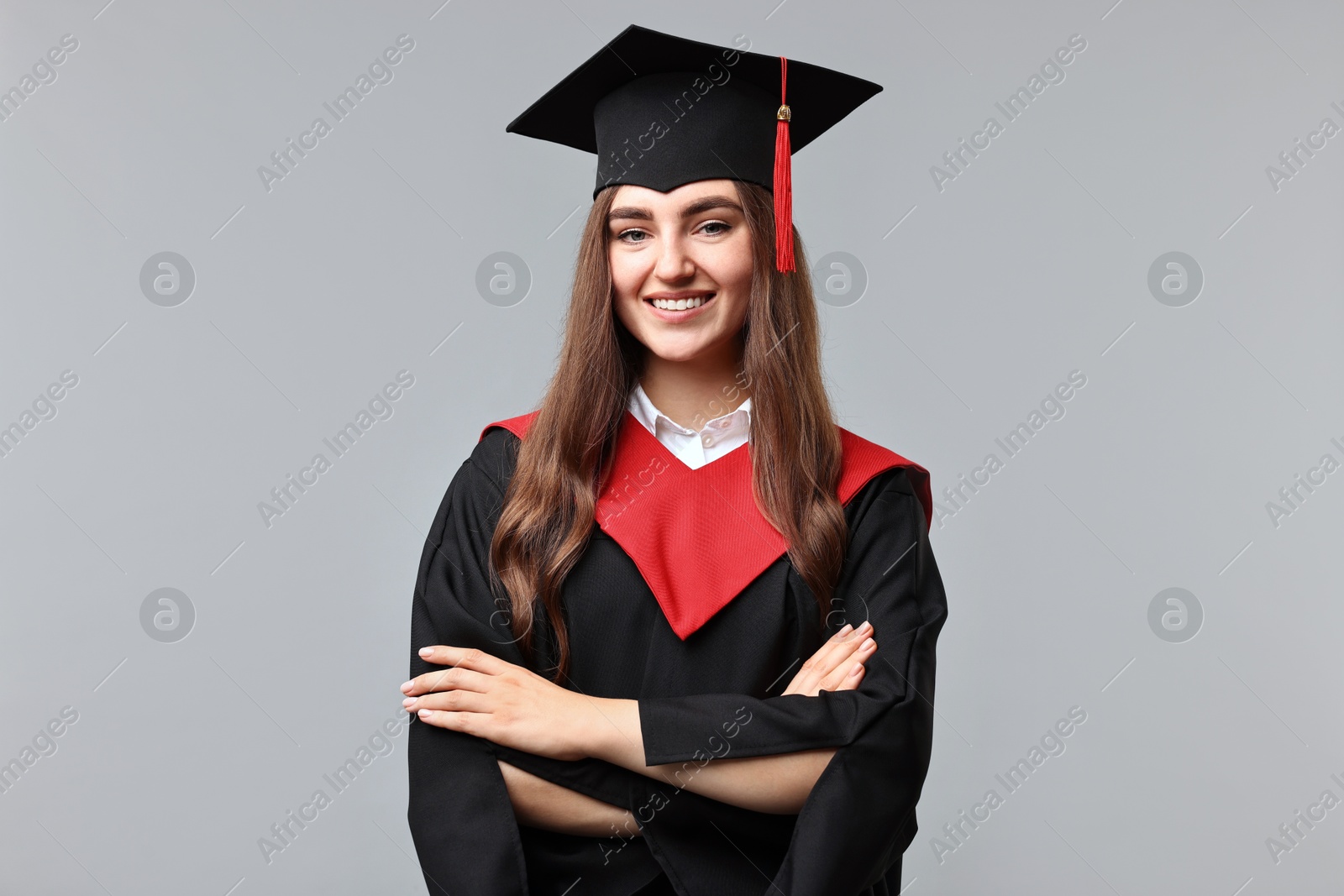 Photo of Happy student with crossed arms after graduation on grey background